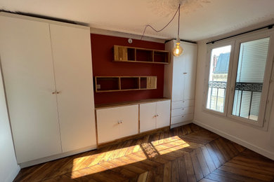パリにある広いおしゃれな主寝室 (赤い壁、無垢フローリング、暖炉なし、茶色い床) のインテリア