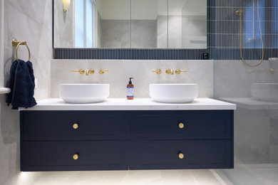 Design ideas for a modern bathroom in Melbourne with shaker cabinets, blue cabinets, a freestanding tub, an open shower, gray tile, porcelain tile, porcelain floors, a vessel sink, marble benchtops, grey floor, an open shower, white benchtops, a double vanity and a freestanding vanity.