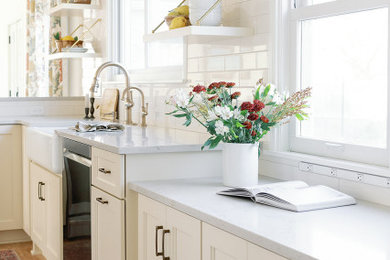 Enclosed kitchen - mid-sized traditional l-shaped light wood floor enclosed kitchen idea in Other with a farmhouse sink, shaker cabinets, white cabinets, quartz countertops, white backsplash, porcelain backsplash, stainless steel appliances, a peninsula and white countertops