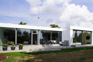 Cette photo montre une façade de maison blanche tendance en stuc de taille moyenne et de plain-pied avec un toit plat.