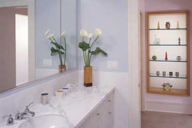 This is an example of a mid-sized contemporary bathroom in San Francisco with flat-panel cabinets, white cabinets, marble benchtops, white tile, ceramic tile and blue walls.