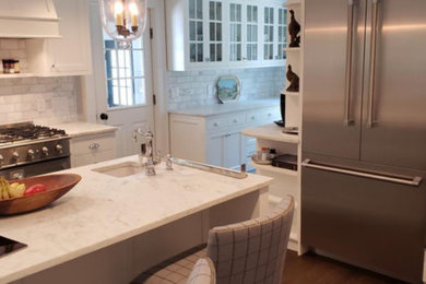 Inspiration for a timeless dark wood floor and brown floor enclosed kitchen remodel in New York with a farmhouse sink, white cabinets, quartzite countertops, white backsplash, marble backsplash, paneled appliances, an island and white countertops