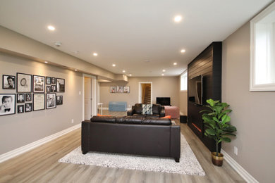 Basement - large transitional look-out laminate floor, beige floor and brick wall basement idea in Ottawa with gray walls, a standard fireplace and a shiplap fireplace