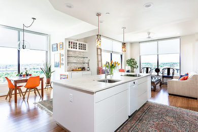 Example of a small transitional galley bamboo floor and brown floor open concept kitchen design in Richmond with a single-bowl sink, flat-panel cabinets, white cabinets, quartzite countertops, beige backsplash, stone tile backsplash, white appliances, an island and beige countertops