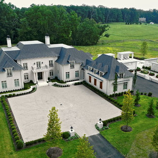 Удачное сочетание для дизайна помещения: огромный, трехэтажный фасад частного дома бежевого цвета в классическом стиле с облицовкой из камня, полувальмовой крышей и черепичной крышей - самое интересное для вас