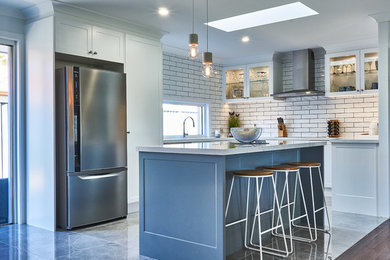 Mid-sized u-shaped open plan kitchen in Gold Coast - Tweed with with island, shaker cabinets, quartz benchtops, white splashback, subway tile splashback, stainless steel appliances, grey floor and grey benchtop.