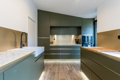 Design ideas for a large contemporary u-shaped separate kitchen in Paris with a drop-in sink, beaded inset cabinets, green cabinets, laminate benchtops, metallic splashback, panelled appliances, ceramic floors, no island, grey floor and white benchtop.