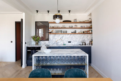 Réalisation d'une cuisine ouverte linéaire et encastrable design de taille moyenne avec un évier 1 bac, un placard à porte plane, des portes de placard bleues, plan de travail en marbre, une crédence en marbre, parquet clair et îlot.