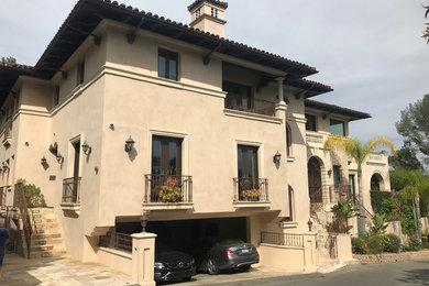 Mid-sized mediterranean beige two-story stucco house exterior idea in Los Angeles with a hip roof and a tile roof