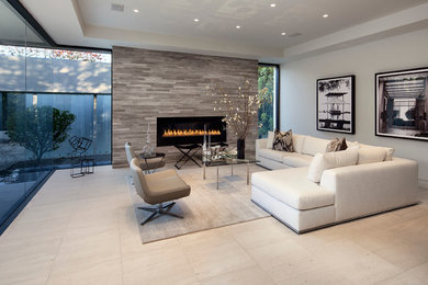 Example of a large trendy formal and open concept travertine floor and beige floor living room design in Los Angeles with gray walls, a standard fireplace, a stone fireplace and no tv