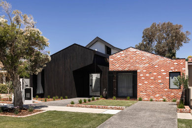 Photo of a mid-sized eclectic one-storey black house exterior in Perth with wood siding, a gable roof, a metal roof, a grey roof and board and batten siding.