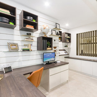 Inredning av ett modernt stort hemmabibliotek, med klinkergolv i keramik, ett inbyggt skrivbord, beiget golv och vita väggar