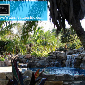Tropical backyard room with pool waterfall, fireplace, and koi pond