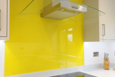 This is an example of a medium sized contemporary galley kitchen/diner in Cambridgeshire with a built-in sink, flat-panel cabinets, grey cabinets, soapstone worktops, yellow splashback, glass sheet splashback, stainless steel appliances, light hardwood flooring, no island, multi-coloured floors and multicoloured worktops.