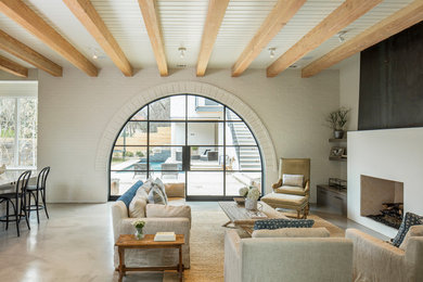 Transitional open concept living room in Austin with white walls, concrete floors and a standard fireplace.
