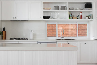 Inspiration for a mid-sized traditional l-shaped open plan kitchen in Sydney with a drop-in sink, shaker cabinets, white cabinets, quartz benchtops, white splashback, stone slab splashback, with island and white benchtop.