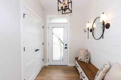 Inspiration for a large cottage medium tone wood floor, brown floor and shiplap wall entryway remodel in Other with white walls and a white front door