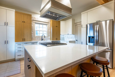 Eat-in kitchen - contemporary u-shaped eat-in kitchen idea in Seattle with an integrated sink, flat-panel cabinets, white cabinets, stone slab backsplash, stainless steel appliances, an island and white countertops