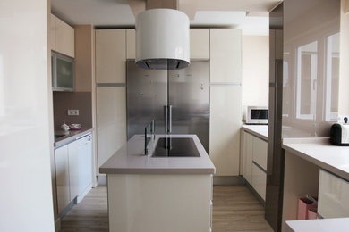 Ejemplo de cocina contemporánea con fregadero bajoencimera, armarios con paneles lisos, puertas de armario beige, encimera de cuarzo compacto, salpicadero de vidrio, electrodomésticos de acero inoxidable, suelo laminado y una isla