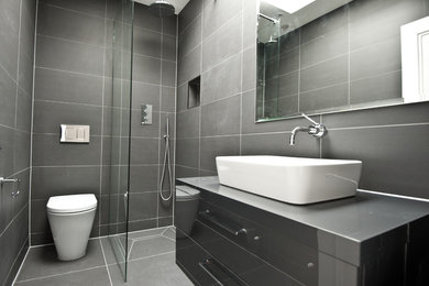 Inspiration for a small contemporary master bathroom in London with grey cabinets, an open shower, a one-piece toilet, gray tile, grey walls, ceramic floors, flat-panel cabinets, ceramic tile and a vessel sink.