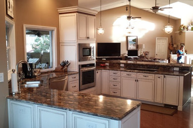 Eat-in kitchen - mid-sized transitional l-shaped dark wood floor and brown floor eat-in kitchen idea in Tampa with an undermount sink, raised-panel cabinets, white cabinets, granite countertops, stainless steel appliances, a peninsula and brown countertops