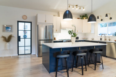 Large danish l-shaped light wood floor, beige floor and vaulted ceiling eat-in kitchen photo in Seattle with an undermount sink, flat-panel cabinets, blue cabinets, quartz countertops, stainless steel appliances, an island and white countertops