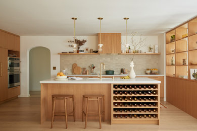 Inspiration for a mid-sized mediterranean u-shaped light wood floor and brown floor eat-in kitchen remodel in San Francisco with a farmhouse sink, flat-panel cabinets, medium tone wood cabinets, quartz countertops, beige backsplash, ceramic backsplash, paneled appliances, an island and gray countertops