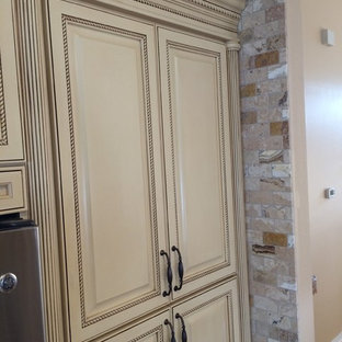 Inspiration for a large arts and crafts u-shaped kitchen pantry in Tampa with an undermount sink, raised-panel cabinets, beige cabinets, granite benchtops, beige splashback, terra-cotta splashback, stainless steel appliances, light hardwood floors and with island.
