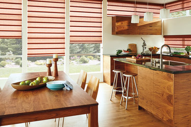 Inspiration for a small mid-century modern l-shaped medium tone wood floor and brown floor eat-in kitchen remodel in New York with a drop-in sink, flat-panel cabinets, medium tone wood cabinets, solid surface countertops, stainless steel appliances and an island
