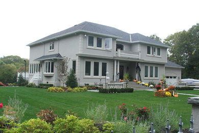 Large transitional beige two-story stucco exterior home photo in New York with a hip roof
