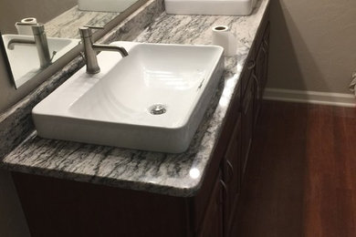 Inspiration for a mid-sized transitional 3/4 gray tile and porcelain tile dark wood floor alcove shower remodel in Indianapolis with raised-panel cabinets, dark wood cabinets, beige walls, a vessel sink and granite countertops