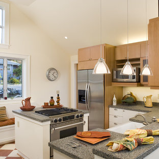 Photo of a contemporary l-shaped kitchen in Seattle with a belfast sink, stainless steel appliances and flat-panel cabinets.