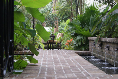 This is an example of a small traditional courtyard partial sun formal garden in Charleston with a water feature and brick pavers.