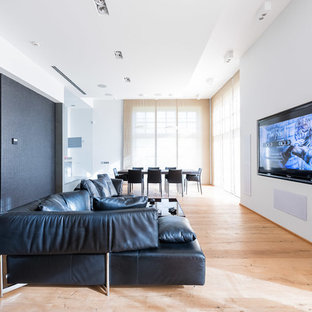 Cette photo montre une grande salle de cinéma tendance ouverte avec un mur blanc, un sol en bois peint et un téléviseur fixé au mur.