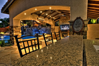 Large arts and crafts backyard stone patio kitchen photo in San Diego with a roof extension