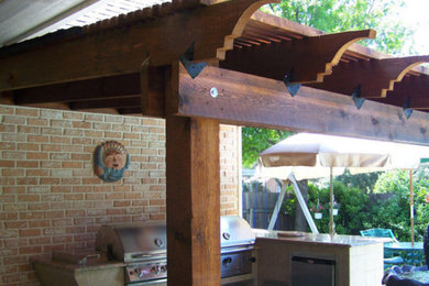This is an example of a small country backyard patio in Dallas with an outdoor kitchen and a pergola.