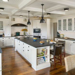 Large beach style kitchen pantry photos - Example of a large coastal u-shaped medium tone wood floor kitchen pantry design in Providence with a farmhouse sink, recessed-panel cabinets, white cabinets, quartzite countertops, white backsplash, subway tile backsplash, stainless steel appliances and an island