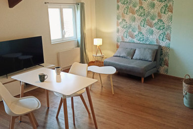 Foto de sala de estar abierta tradicional de tamaño medio sin chimenea con paredes blancas, suelo de madera clara, televisor independiente, suelo marrón, vigas vistas y papel pintado