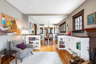 Arts and crafts open concept light wood floor and multicolored floor family room photo in Detroit with beige walls, a standard fireplace and a brick fireplace