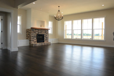 Example of a large cottage formal and open concept dark wood floor living room design in Other with beige walls, a standard fireplace, a brick fireplace and a media wall