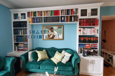 Diseño de biblioteca en casa abierta y blanca clásica renovada de tamaño medio con paredes azules y suelo de madera clara