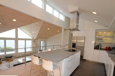 Example of a huge trendy galley light wood floor open concept kitchen design in Orange County with flat-panel cabinets, white cabinets, quartz countertops, stainless steel appliances and an island