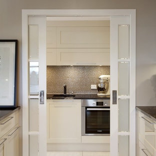 Large contemporary kitchen pantry designs - Large trendy galley ceramic floor kitchen pantry photo in Auckland with recessed-panel cabinets, white cabinets, granite countertops, brown backsplash, mosaic tile backsplash, stainless steel appliances and an island