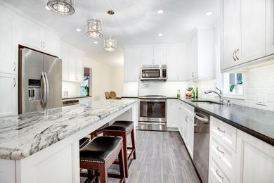 Mid-sized traditional l-shaped separate kitchen in Orlando with shaker cabinets, white cabinets, granite benchtops, white splashback, subway tile splashback, stainless steel appliances, porcelain floors, with island and grey floor.