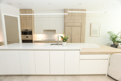 Kitchen - large mid-century modern l-shaped ceramic tile and beige floor kitchen idea in Austin with an undermount sink, flat-panel cabinets, light wood cabinets, quartzite countertops, gray backsplash, paneled appliances, an island and white countertops