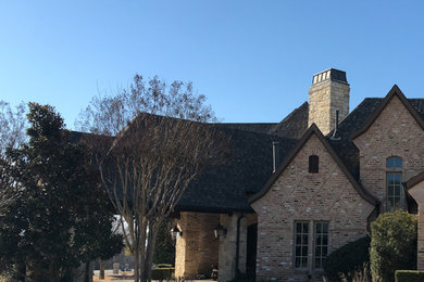 This is an example of a large traditional two-storey brick blue house exterior in Dallas with a hip roof and a shingle roof.