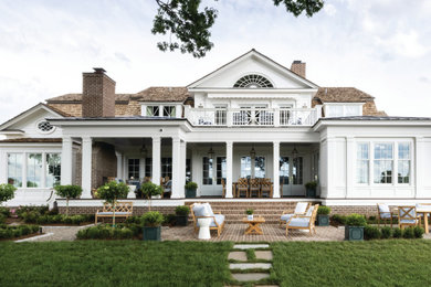 Large french country white two-story board and batten house exterior photo in Louisville with a shingle roof and a brown roof