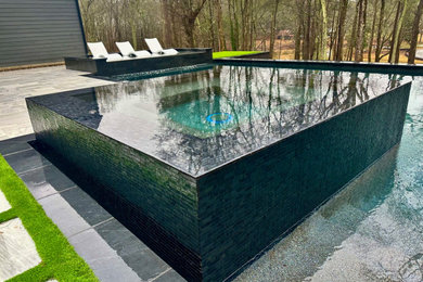 Réalisation d'une petite piscine à débordement et arrière minimaliste sur mesure.