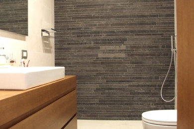 Idee per una stanza da bagno con doccia design di medie dimensioni con ante lisce, ante in legno bruno, doccia a filo pavimento, WC a due pezzi, pistrelle in bianco e nero, piastrelle in gres porcellanato, pareti bianche, pavimento in gres porcellanato, lavabo a bacinella, top in legno, pavimento grigio, porta doccia scorrevole e top marrone