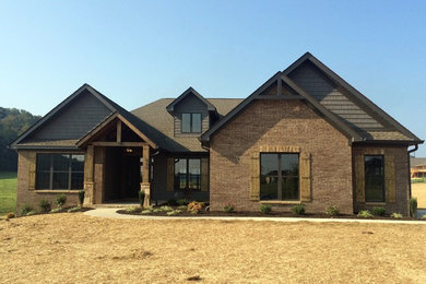 Example of a mid-sized arts and crafts red one-story brick gable roof design in Other